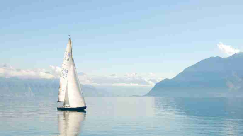 Sailing boat glides peacefully on a misty lake surrounded by mountains, under clear daylight., tags: de van - pexel
