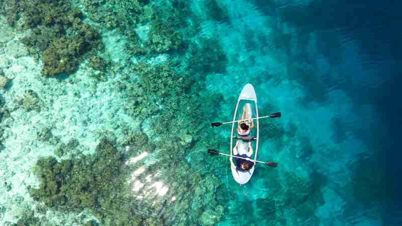 Aerial view of clear canoe gliding over vibrant coral reefs in the Maldives' turquoise waters., tags: vanuit - pexel